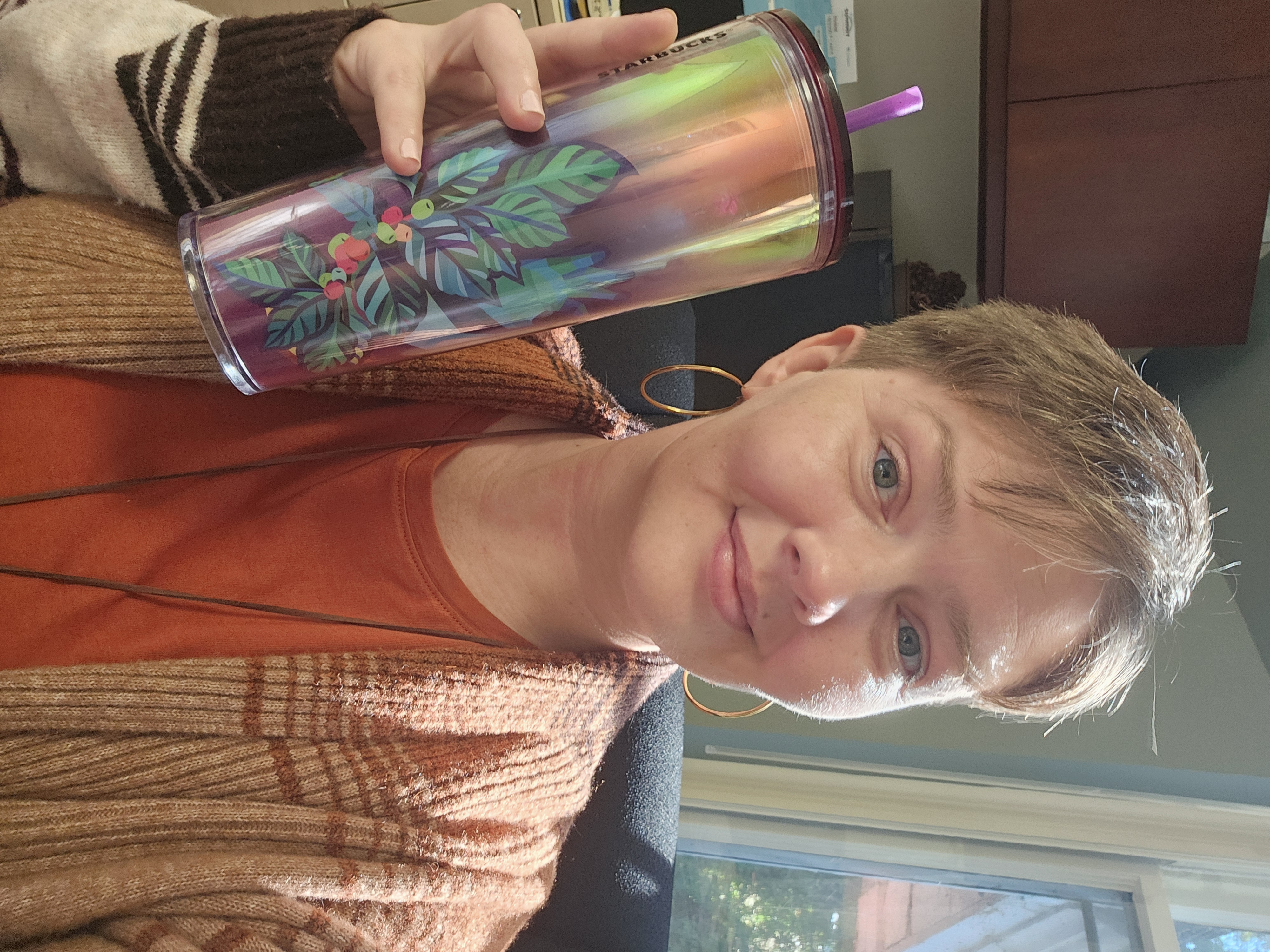 A woman holds a tall plastic cup with a straw