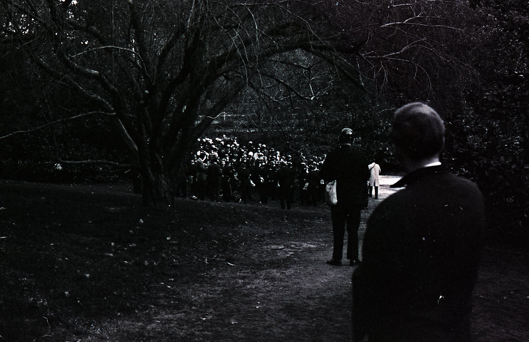 A black and white photo shows a very dark image of a crowd of Duke Police gathered in the Sarah P. Duke Gardens