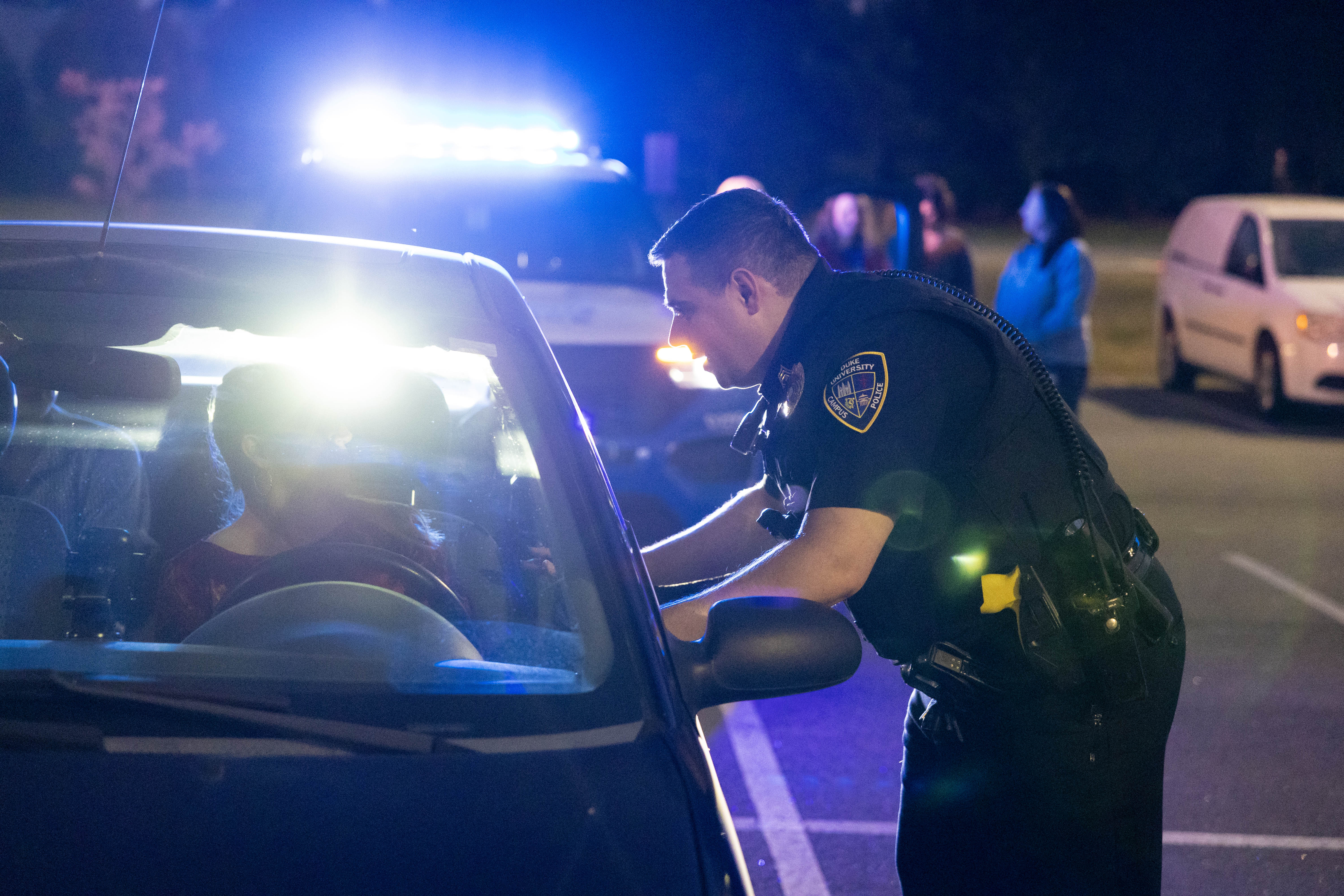 A police officer leans into the window of a car to talk to driver during a mock traffic stop