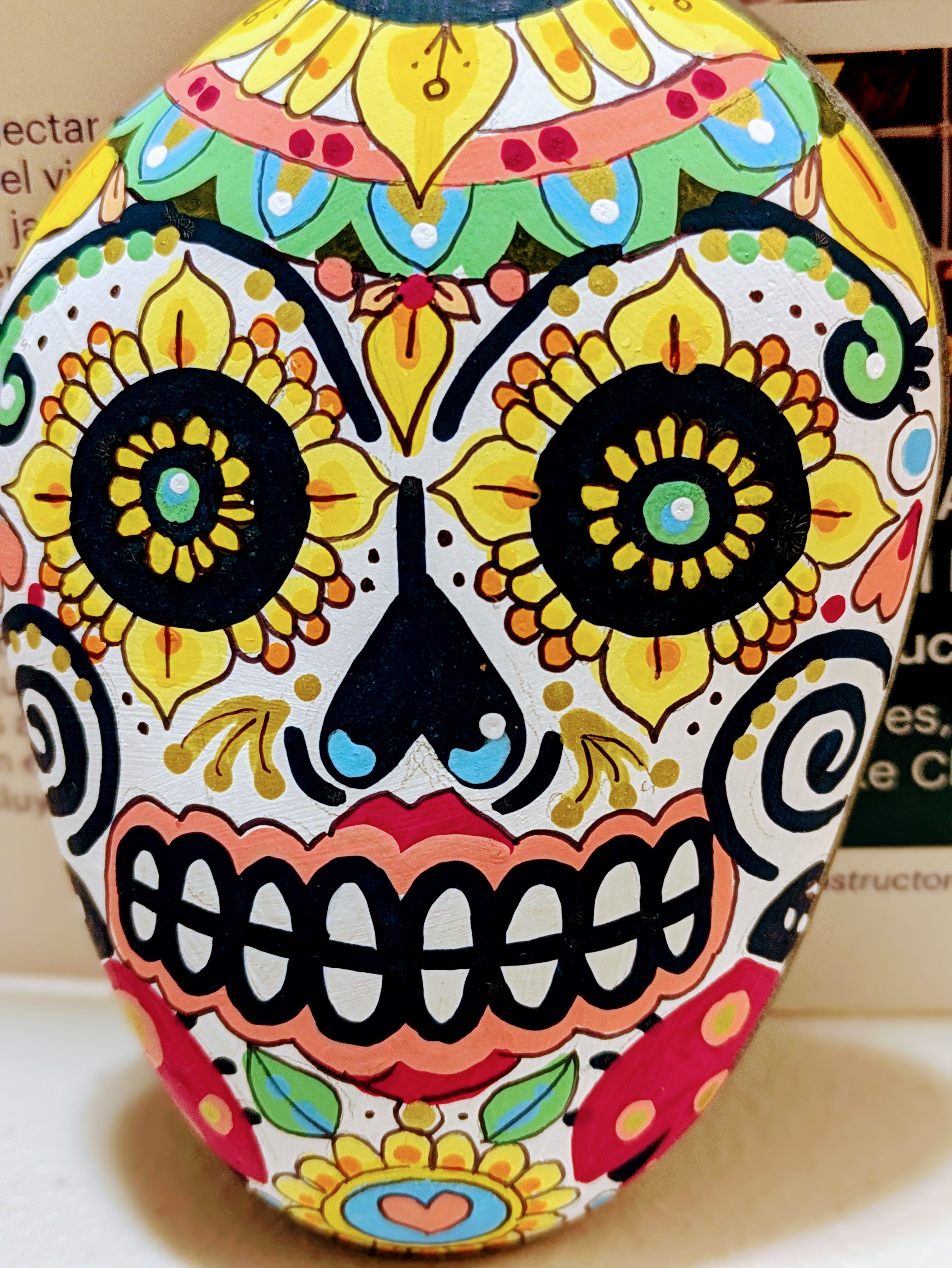 a decorative rock is painted to look like a Day of the Dead skull