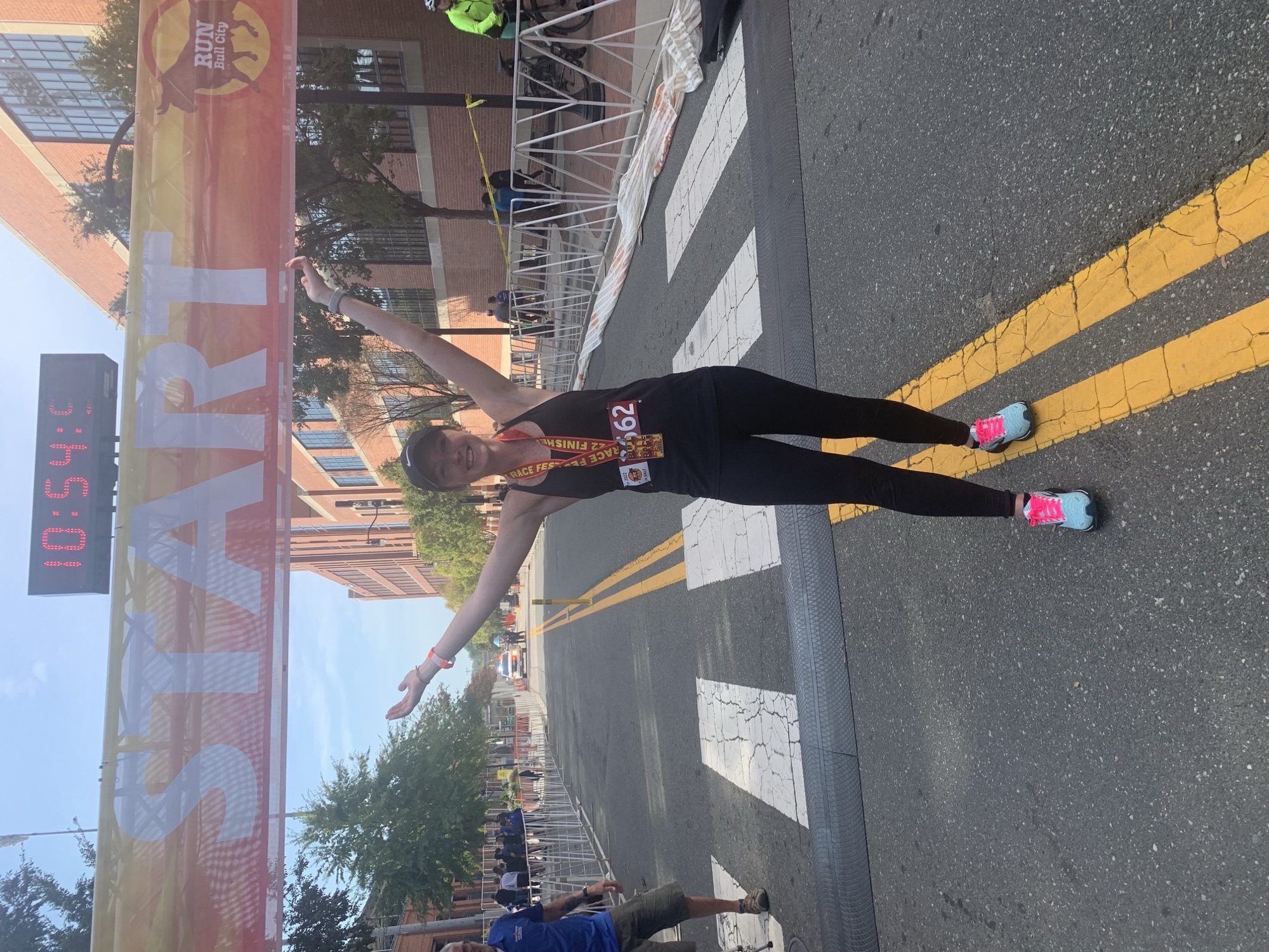 A woman stands at the start/finish line of half marathon