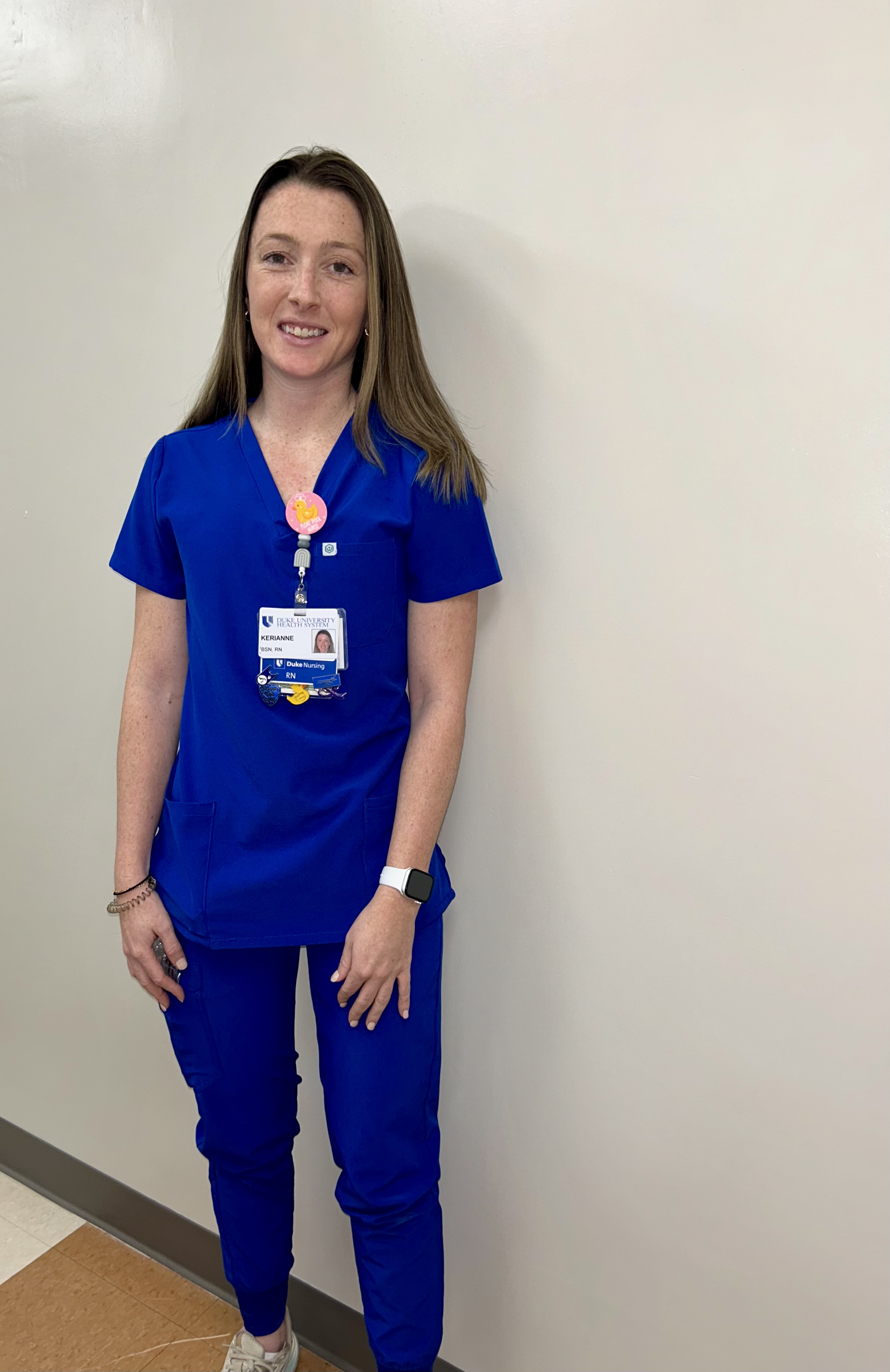 A woman stands in blue scrubs