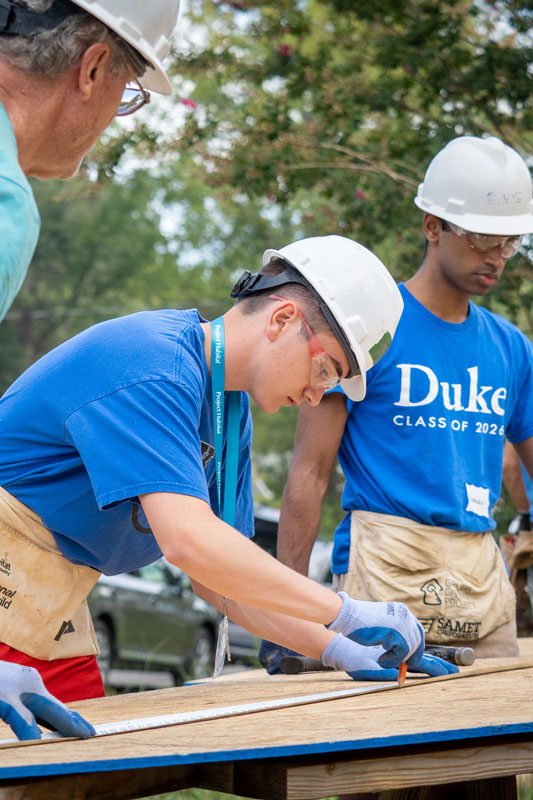 Students in hard hats helping to build a house for Habitat for Humanity during experiential orientation