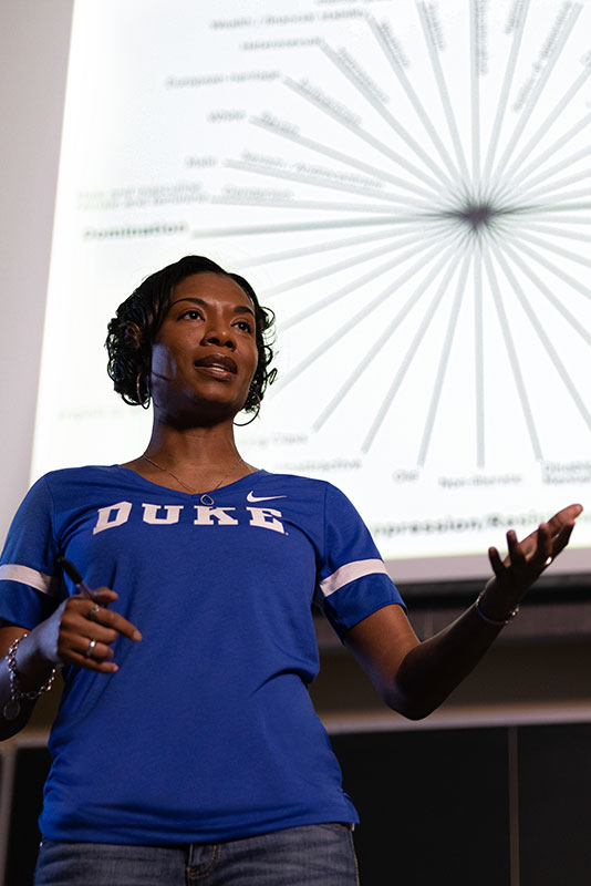 Nicki Washington presenting in front of a project image with radial lines