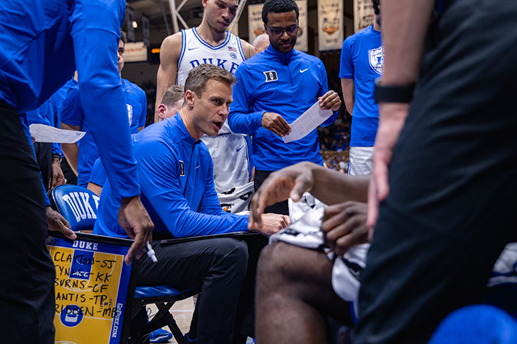 Duke men's basketball coach Jon Scheyer instructs the team from the center of a huddle