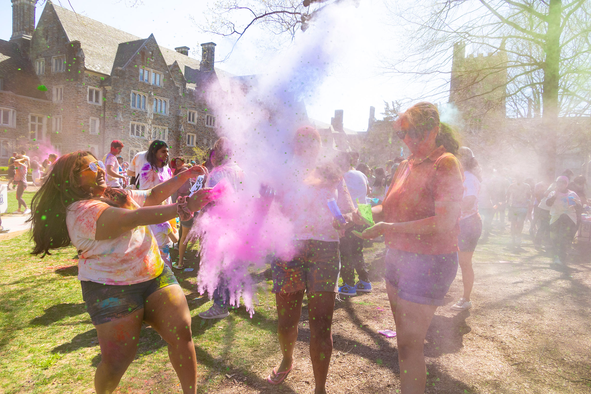 three women toss holi dust in the air
