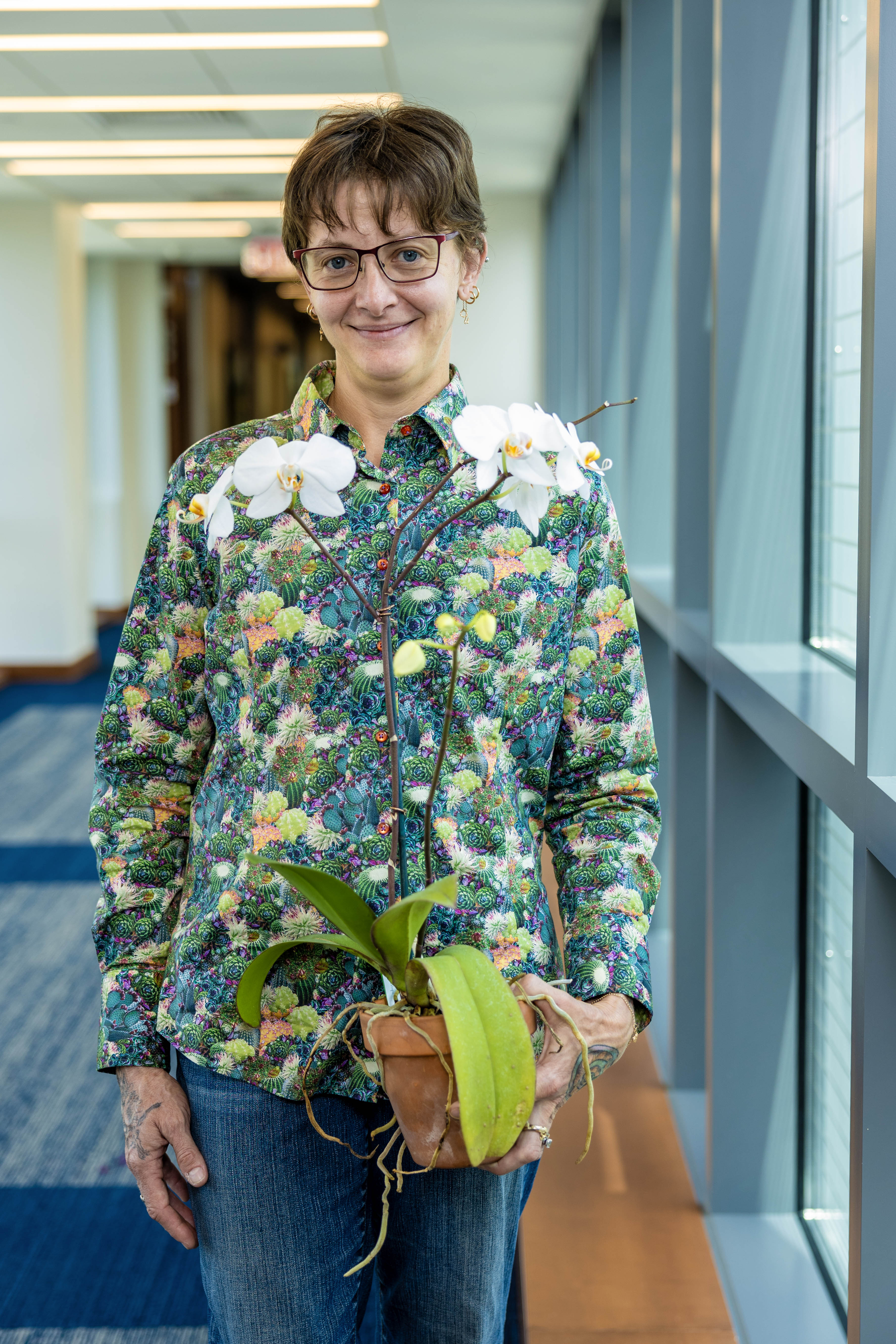 A woman stands holding an orchid plant