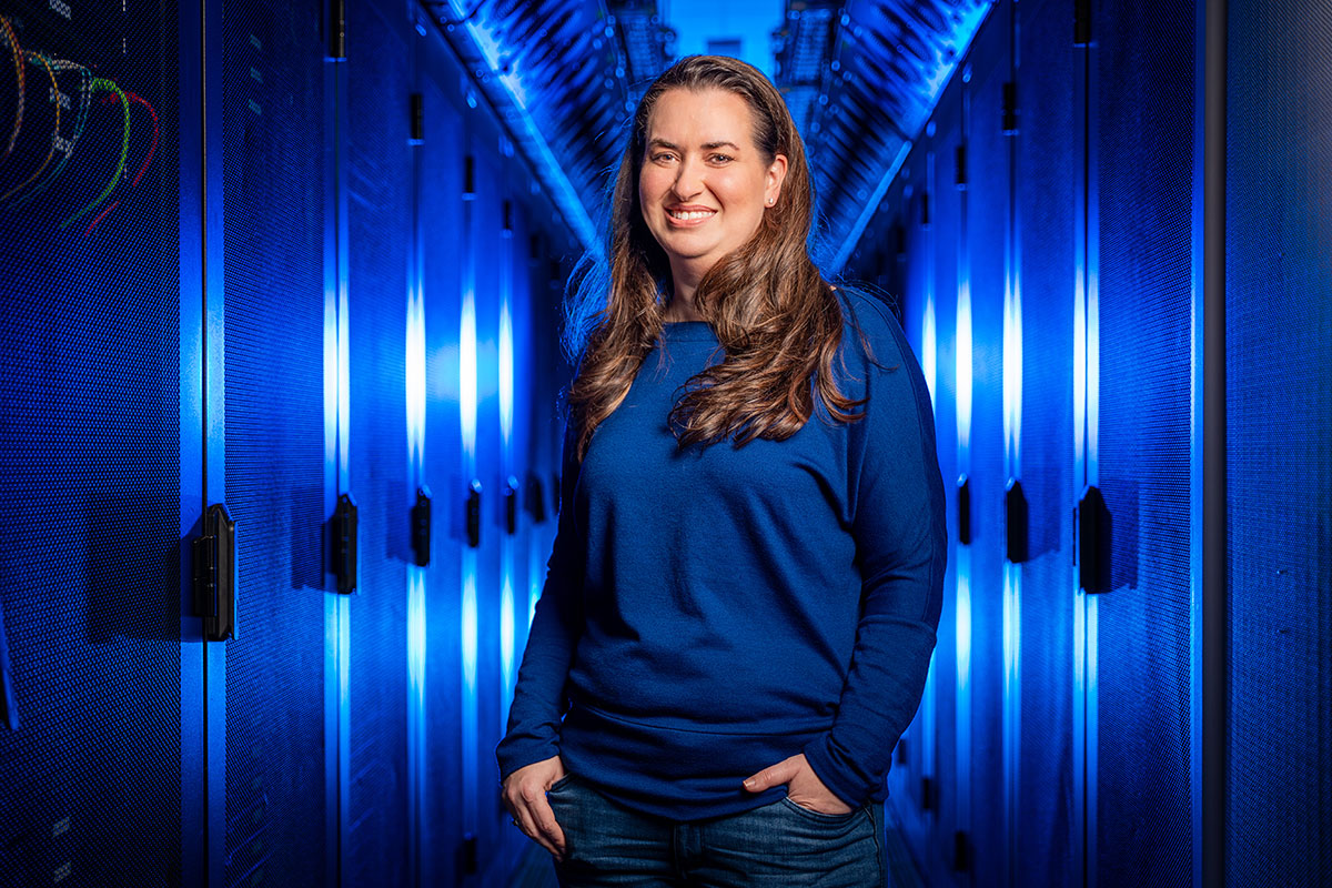 Amanda Randles standing in a server room lit with a blue light