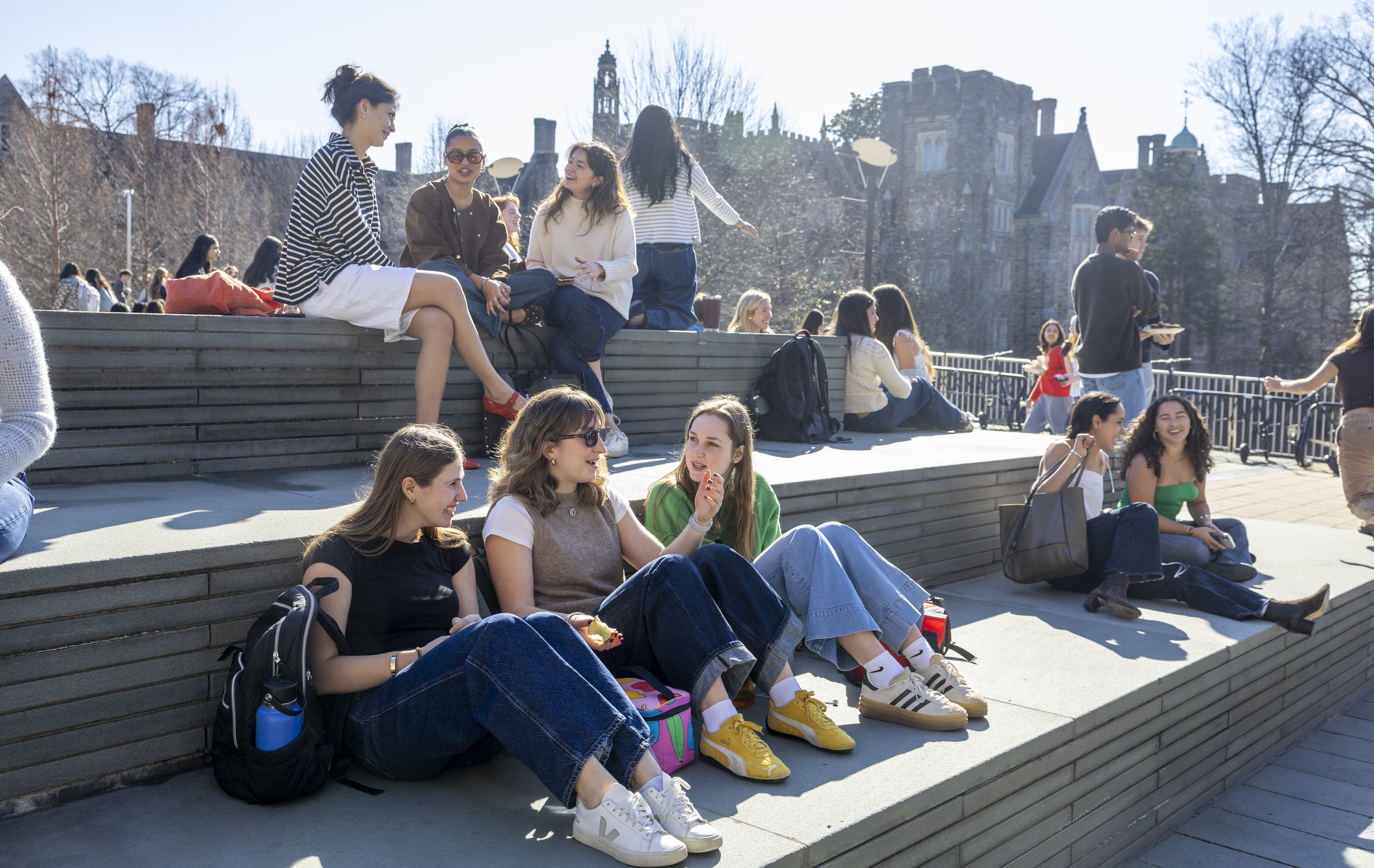 Students sit and chat with each other in the sun