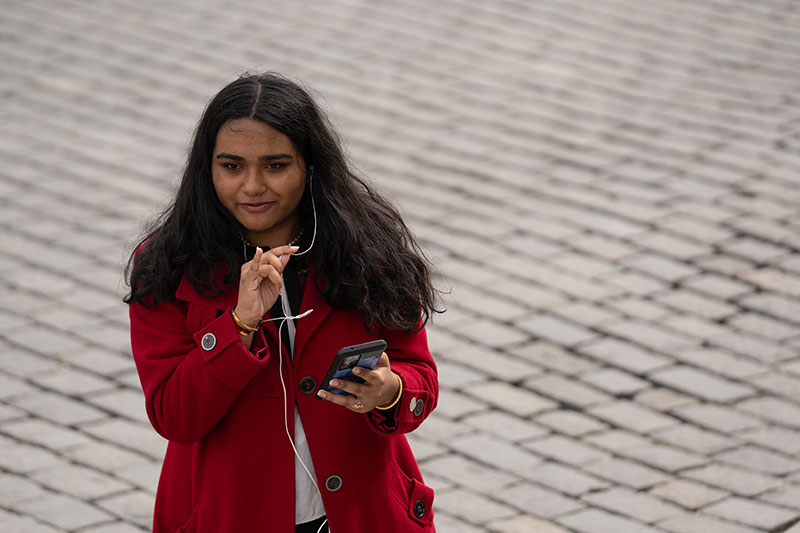 A student holding their phone delivering their talk on a cobblestone street