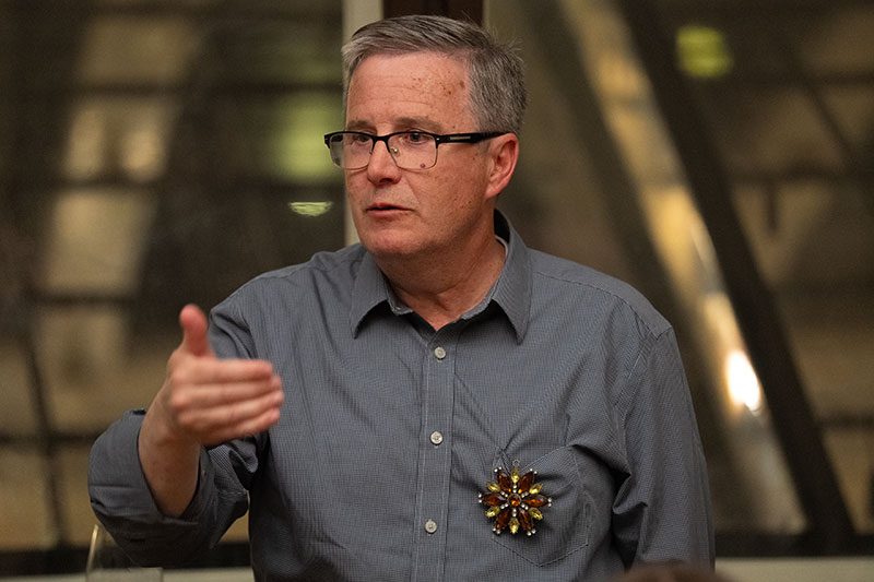 Peaver Fever gesturing as he presents, wearing an amber and gold, circular brooch