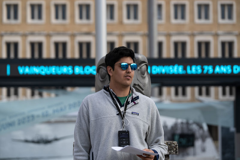 A student in blue reflective sunglasses stands in front of an eagle statue