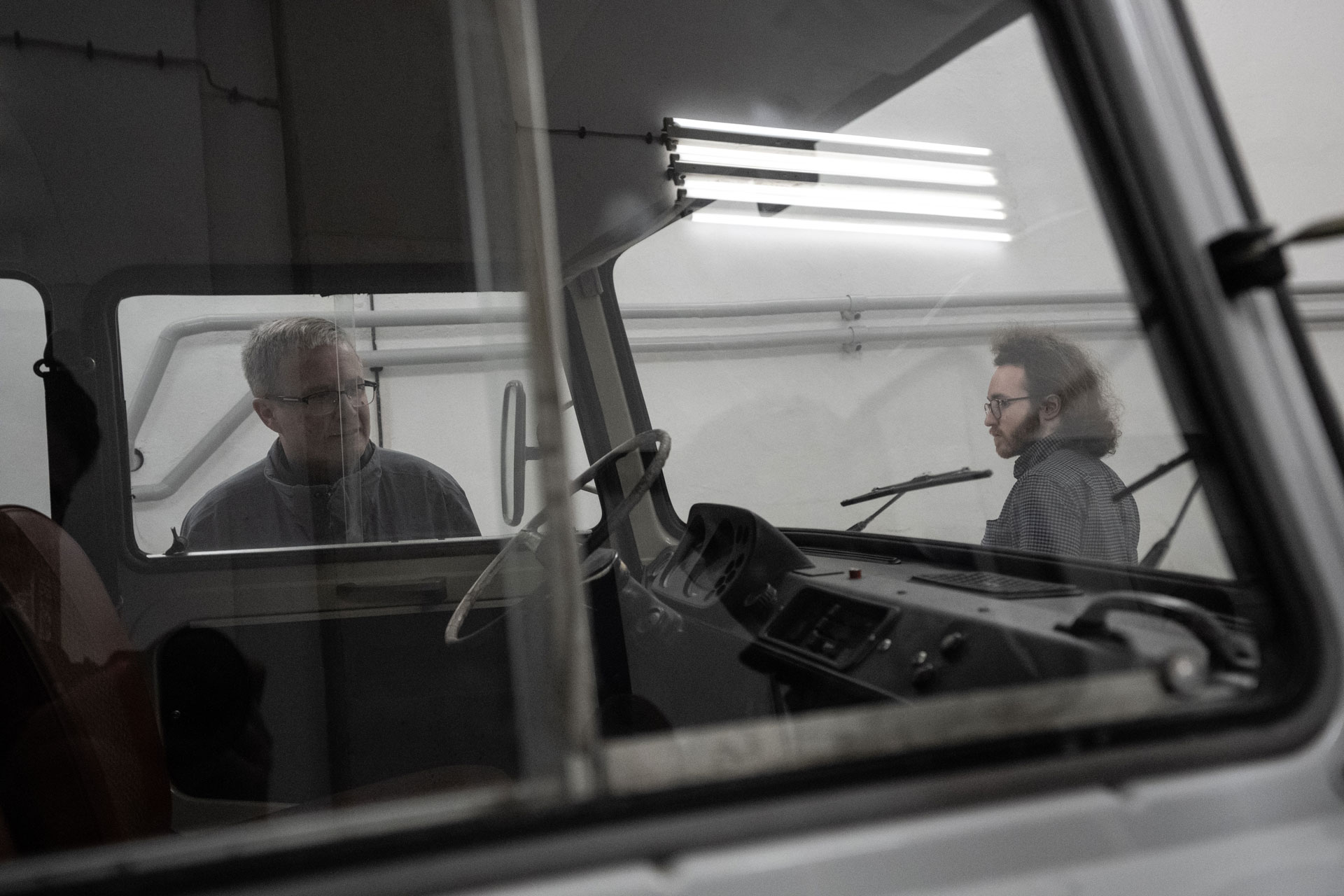A view through the windows of an old van with two people in the background