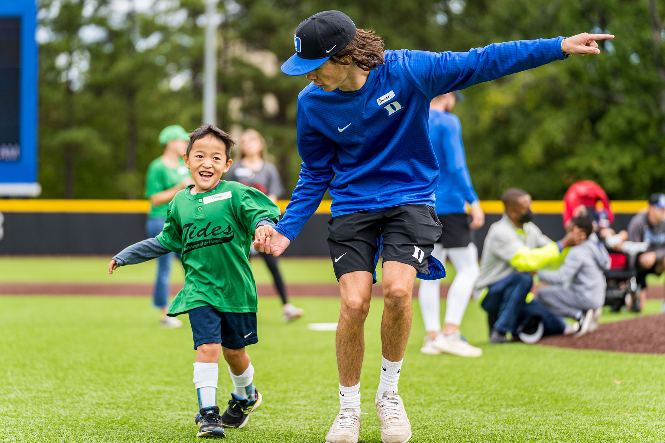 A Miracle League player is helped around the basepaths at Duke’s Coombs Stadium by a Duke baseball player.