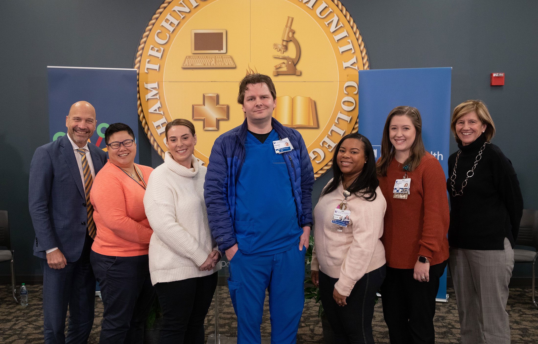 Dr. Craig Albanese and Dean Mary Klotman flank a group of Durham Tech graduates who now work at Duke Health.