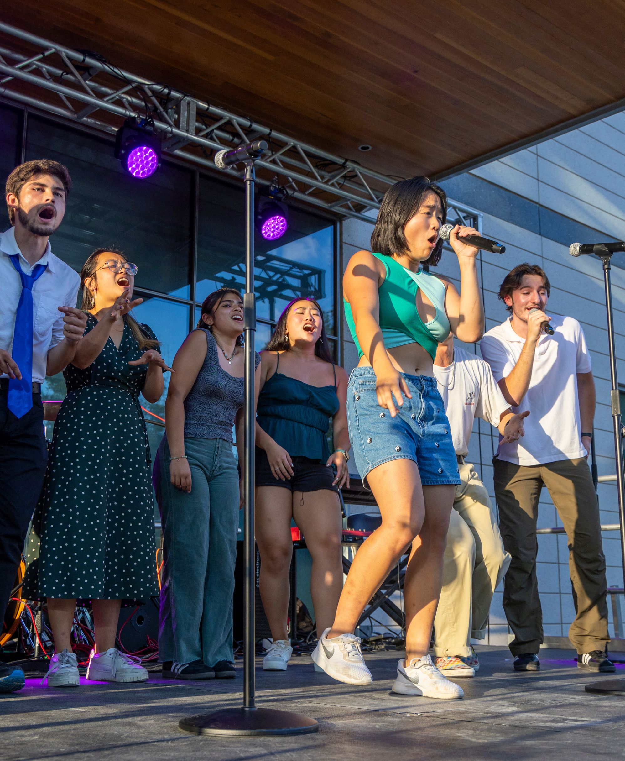 Students stand in a semi-circle singing with one student singing in front.
