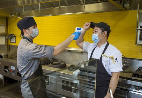 Min Aung, supervisor of Ginger + Soy, performs a temperature check and screens chef Jae Won for any symptoms as he arrives for work, as part of Duke University’s response to the COVID-19 pandemic. 