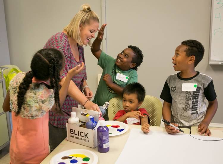 Students laugh and play with therapist Mallory Schellhorn as they prepare paint for their project. Photo Jared Lazarus