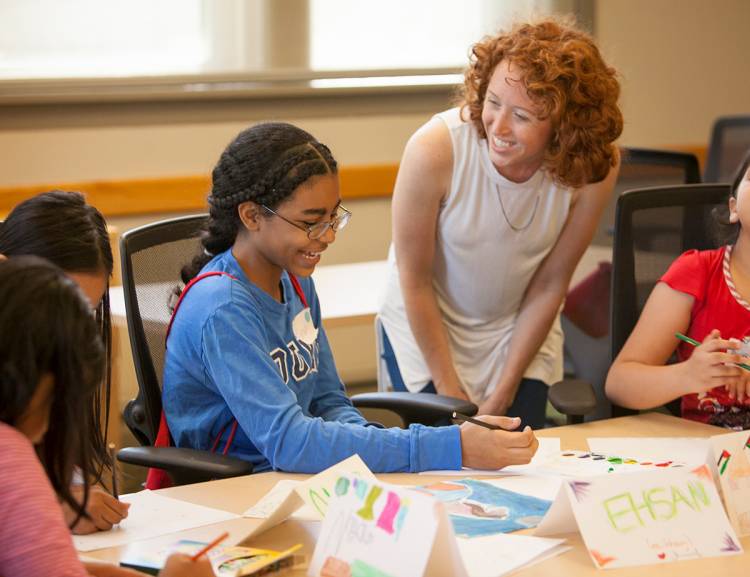 Graduate intern Samantha Boyce assists a student from Sudan with her art project. Photo by Jared Lazarus