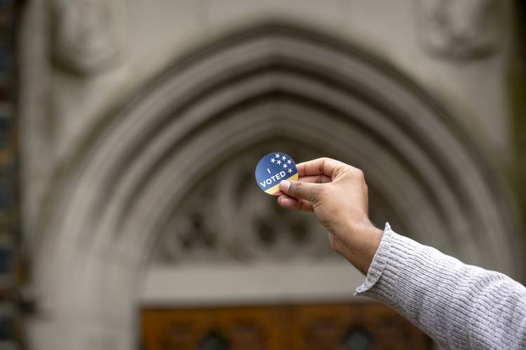 An 'I voted' sticker held up against Duke's architecture.