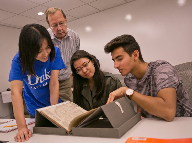 Professor Tom Robisheaux looks on as FOCUS students examine a book from the Renaissance. Photo by Megan Mendenhall/Duke Photography