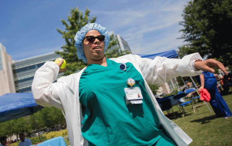 Chelsi Lawless, RN, winds up to throw at Dr. Jon Routh during the Dunk-A-Doc fundraising event at Duke Cancer Center on May 16, 2019. Eighteen doctors volunteered to get wet to support cancer research and raise awareness about the new DCI Center for Prost