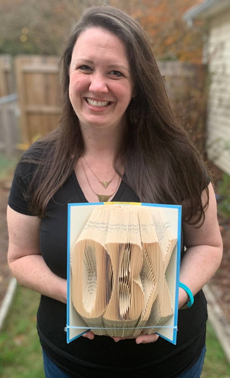 Anna Jackson holds a piece of folded book art that says OBX. Photo courtesy of Anna Jackson.