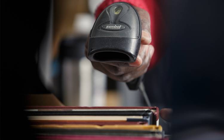 Library Assistant Emmanuel Senga tracks returned books with a barcode reader. Photo by Alex Boerner.