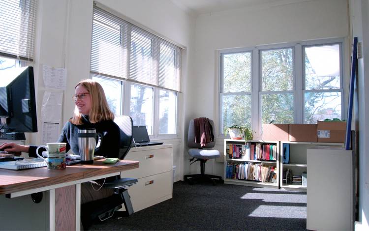 Barbara Thompson, an IT analyst with Duke Continuing Studies, works on a converted porch on the second floor of Bishop's House. Photo by Stephen Schramm.