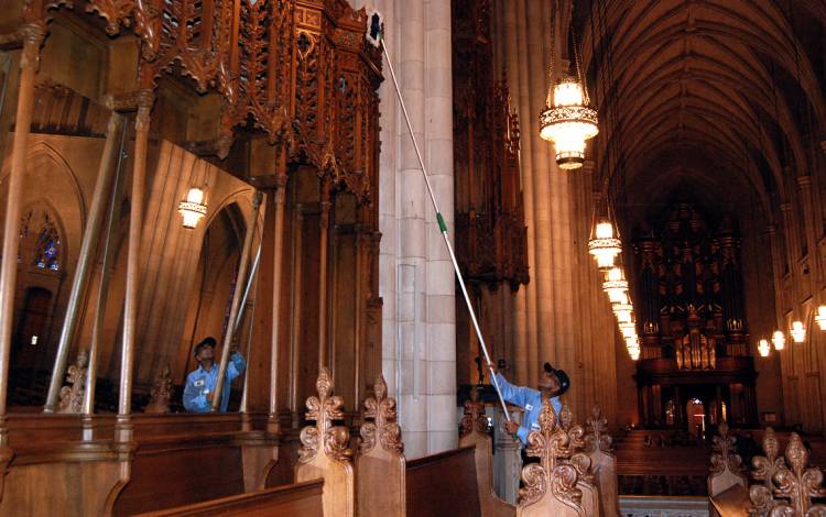 Utility Worker Oscar Dantzler uses a specialized pole to dust part of Duke University Chapel's interior. Photo by Stephen Schramm.