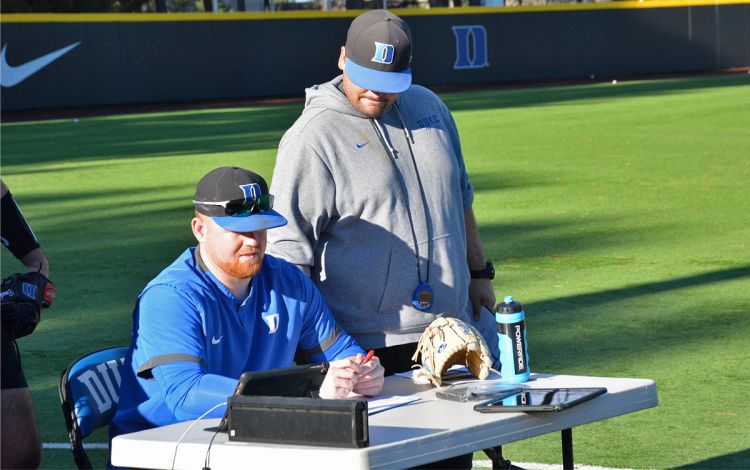 Coleman Williams, left, and Pitching Coach Chris Gordon, right, check data during a recent practice. Photo by Stephen Schramm.