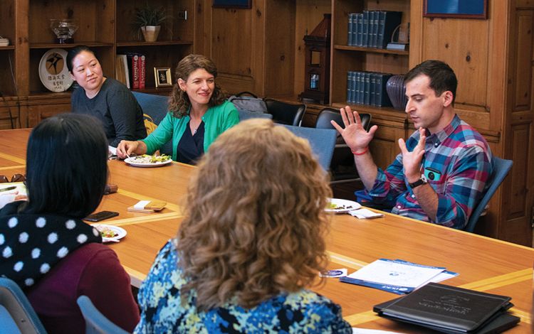 Maria Wisdom, in green, sits around the table and listens to conversation during a recent coaching session. Photo courtesy of Maria Wisdom.