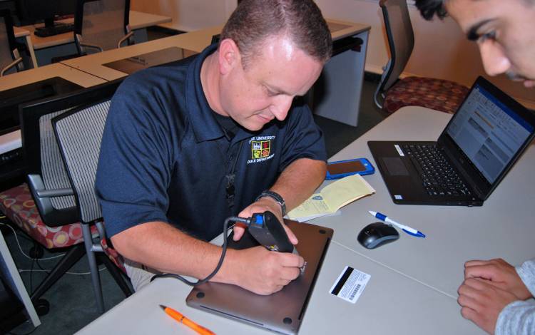 Kelly George of the Duke University Police Department engraves a student's laptop. Photo by Stephen Schramm.