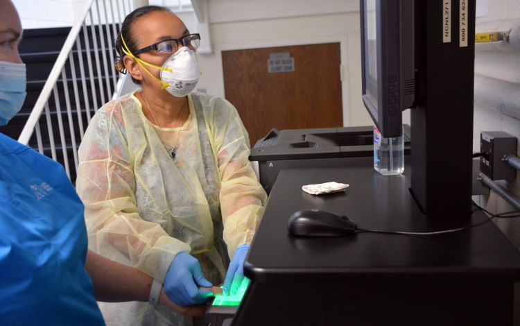 The Duke University Police Department's Lila Rose Edwards gathers fingerprints from a Duke colleague. Photo by Stephen Schramm.