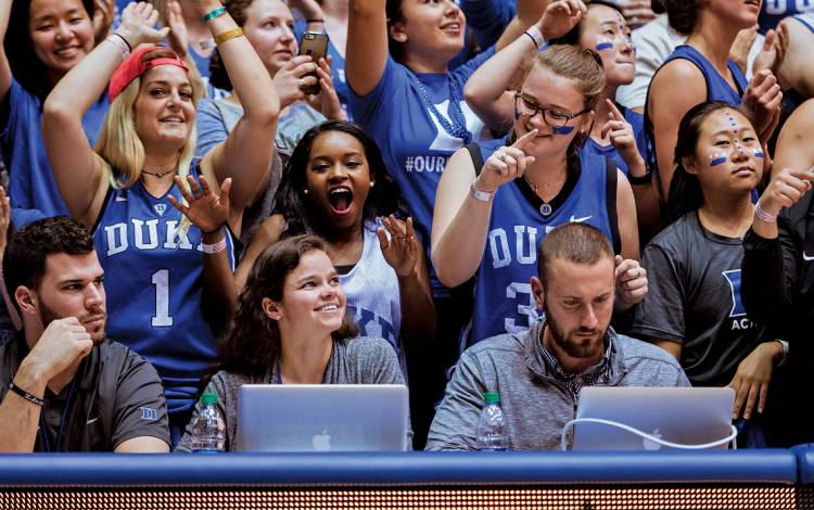 Jess McNamera, social media manager for Duke Athletics, seated second from left, works on press row in Cameron Indoor Stadium during the last home game for the Men’s Basketball team on February 28, 2017.