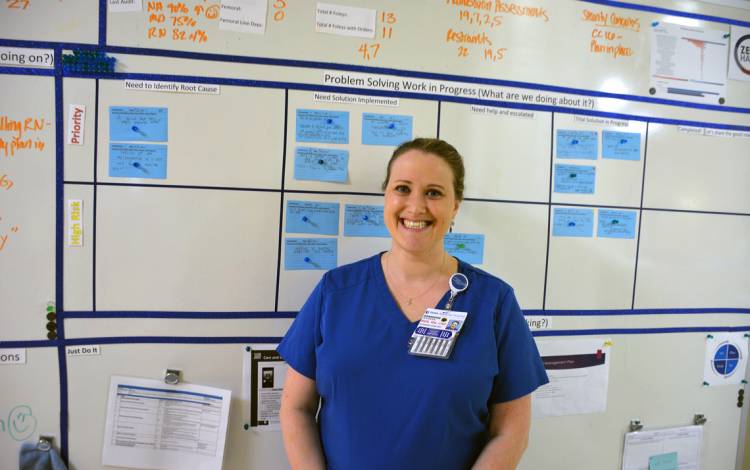 Jenny Urban stands in front of a whiteboard Duke Regional Hospital's Intensive Care Unit uses to track their ideas. Photo by Jonathan Black.