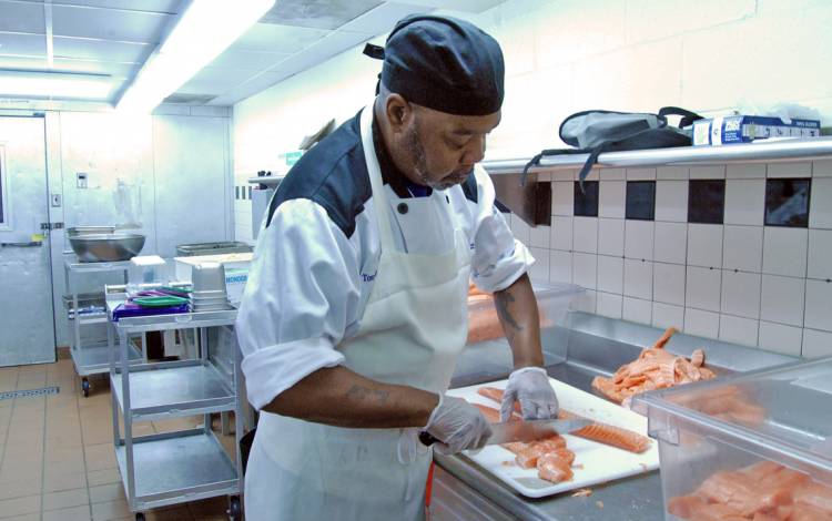 Duke Dining Duke Dining's Tony Smith portions salmon a few days before the Thanksgiving meal at East Campus Marketplace. Photo by Stephen Schramm.