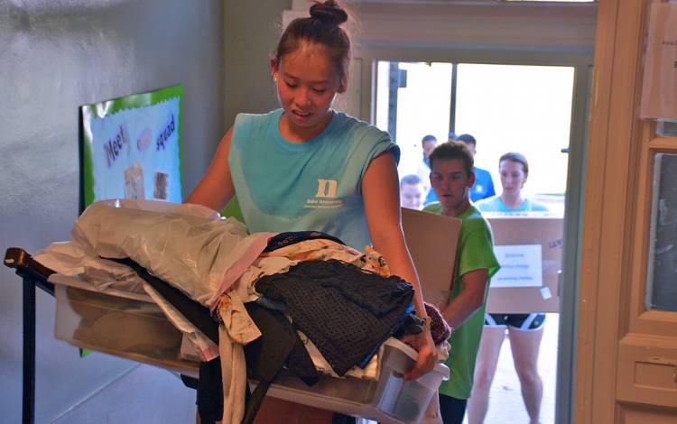 Students with the First Year Advisory Council, which helps transition incoming first-year students to college life, carry luggage to a residence hall on East Campus. 