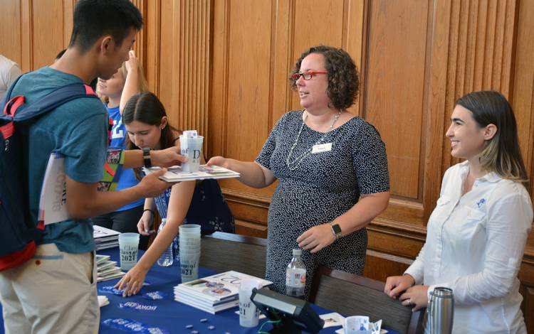 Inga Peterson, assistant vice president of alumni affairs, and Sara Stevens, staff assistant, distribute directories to students in the East Campus Union along with a Class of 2021 mug.