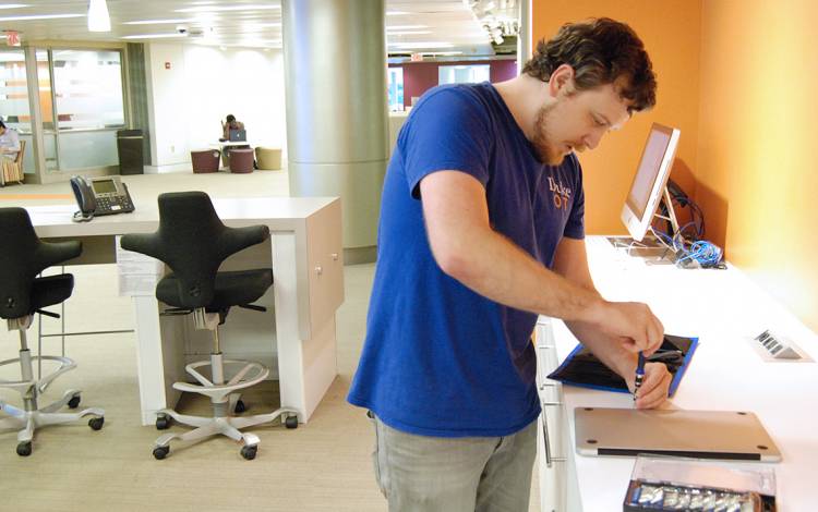 Erik Piper fixes a computer at the OIT Service Desk's walk-up facility at Perkins Library.