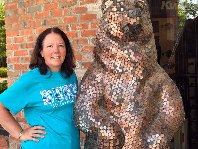 Patti Silver poses next to a bear statue covered in pennies.