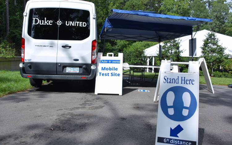 Signs direct people where to stand while waiting to self-administer their COVID-19 tests at the mobile van testing site.