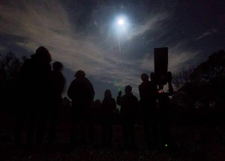 Ronen Plesser, Physics professor and Duke Teaching Observatory instructor, holding laser pointer, talks about the various star clusters visible in the sky as community members stargaze in Duke Forest. Photo by Jared Lazarus, Duke University.