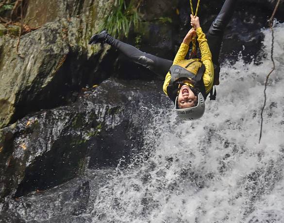 Simone Pitre rides a zipline over a roaring river.