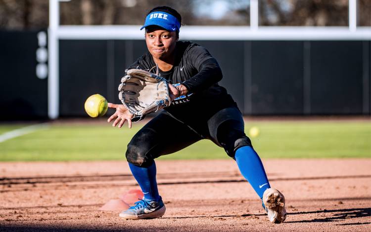 A softball player fields a ground ball.