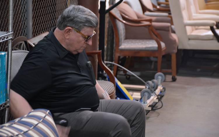 Tom Hunter tests out a chair at the Duke Surplus warehouse. Photo by Jonathan Black.