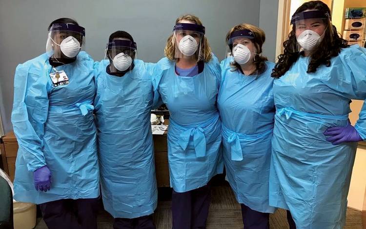 Duke Urgent Care South employees Dawn Williams, Anthony Jones, Angela Jones, Liz Donohue and Gina Moore stand at a Duke ambulatory COVID-19 site in March.