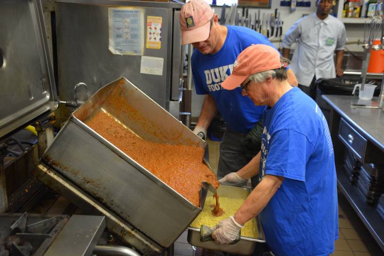Karl Bates, left, and Geoffrey Mock add spaghetti sauce to the pasta in the Urban Ministries kitchen. 