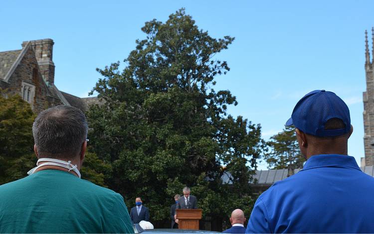 Jim McKinnon, left, and Nate Bonham, right, listen to Duke Vice President for Administration Kyle Cavanaugh give his remarks. Photo by Stephen Schramm.
