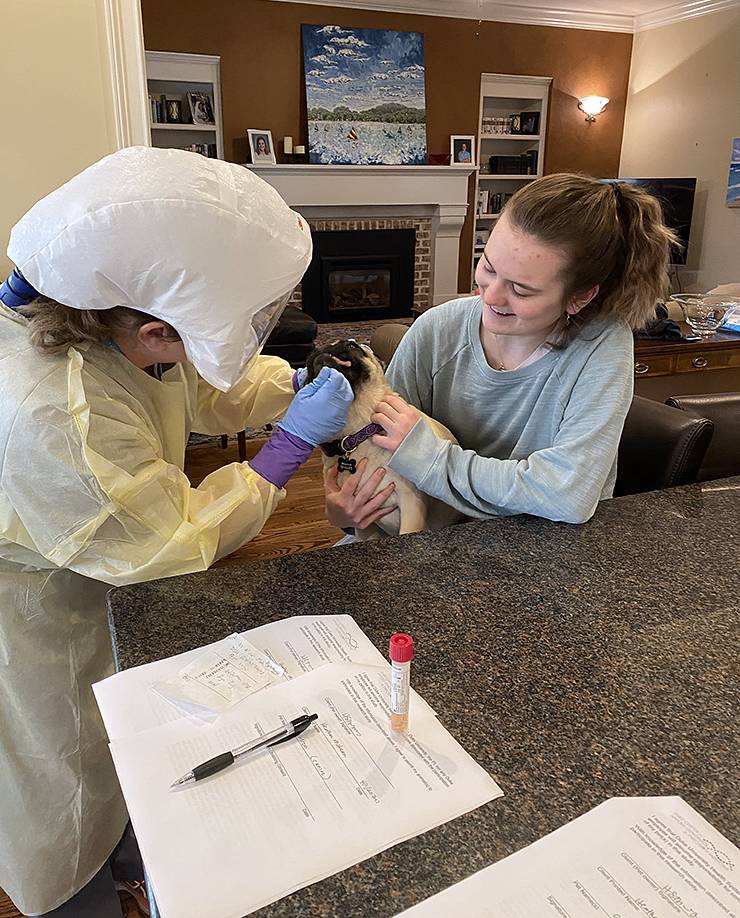 Sydney McLean, right, holds Winston while he receives an oral swab from a Duke researcher. Photo courtesy of Heather McLean.